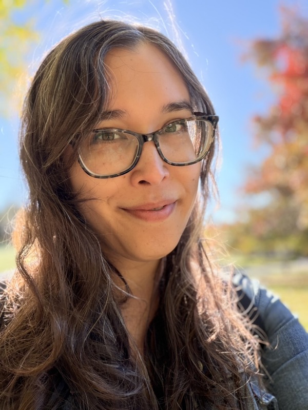 Amy smiling outdoors on a sunny fall day